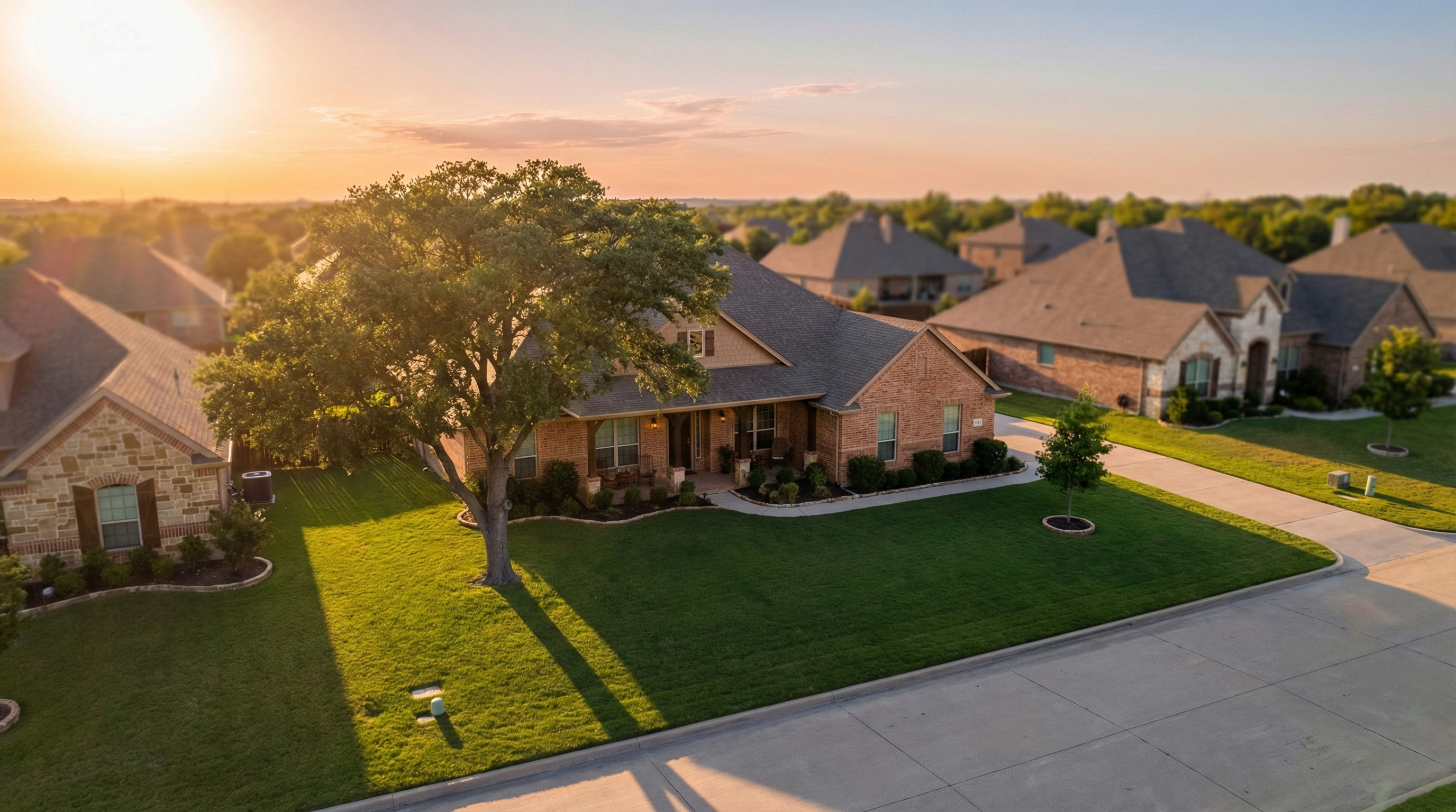 Aerial view of a Texas suburban neighborhood at golden hour with well-maintained ranch-style homes and manicured lawns